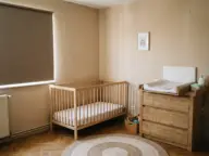 Camera bebelușului cu pătuț cu saltea fermă și nimic altceva în el, comodă de înfășat ancorată și rulou opac