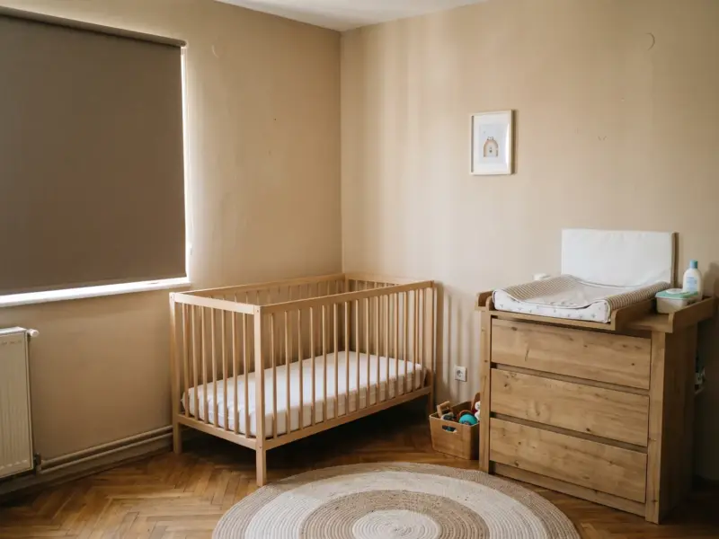Camera bebelușului cu pătuț cu saltea fermă și nimic altceva în el, comodă de înfășat ancorată și rulou opac