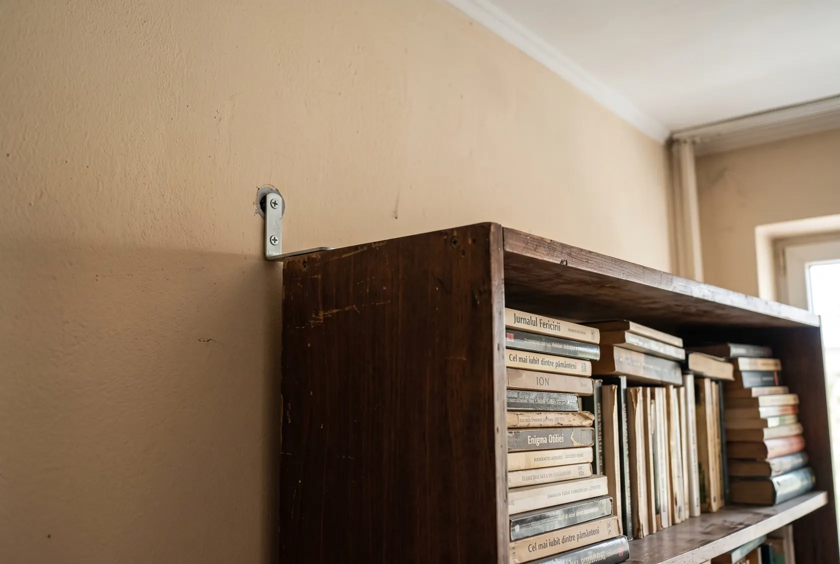 Colțar metalic de ancorare între partea de sus a bibliotecii și perete, cu șurub și diblu