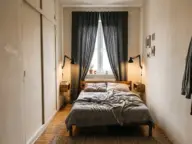 Dormitor mic cu patul așezat longitudinal sub fereastră, dulap puțin adânc cu uși glisante și noptiere suspendate
